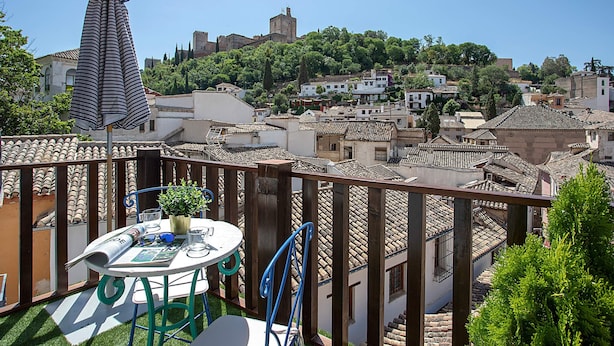 A terrace with a table, chairs, and a striped umbrella.