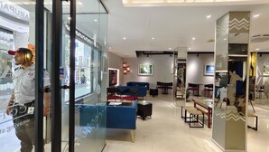 A modern hotel lobby with glass partitions, seating areas, and a visible restaurant named "KARUPURAM." - Hotel Nandini (Dhaka)
