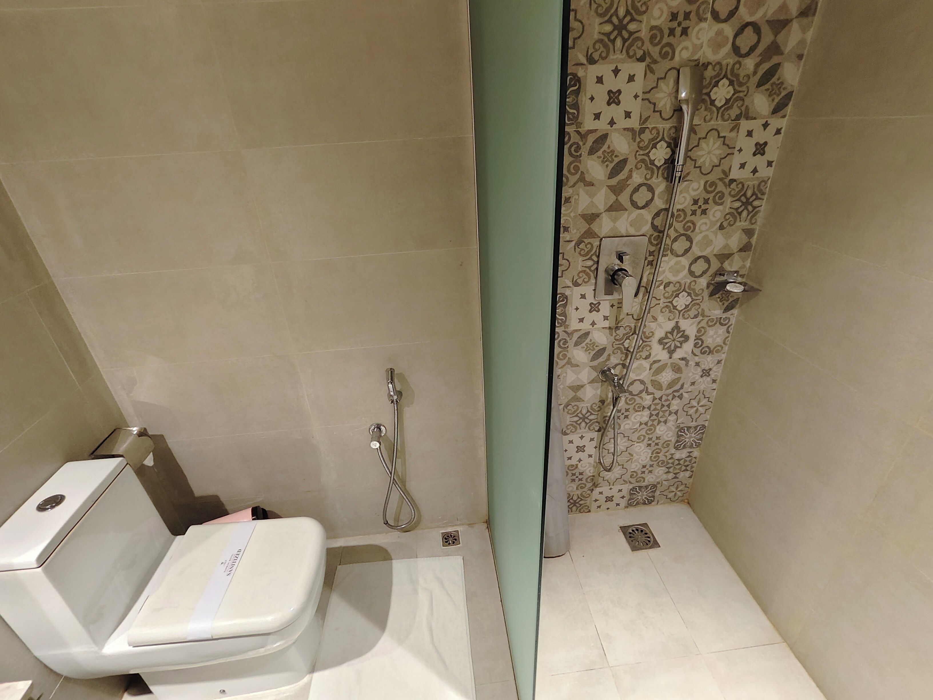 A bathroom with a toilet, shower, and a patterned wall.