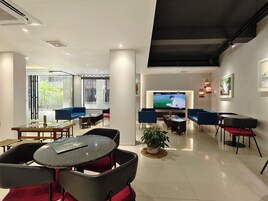 A modern living room with a flat-screen TV, comfortable seating, and a large window.