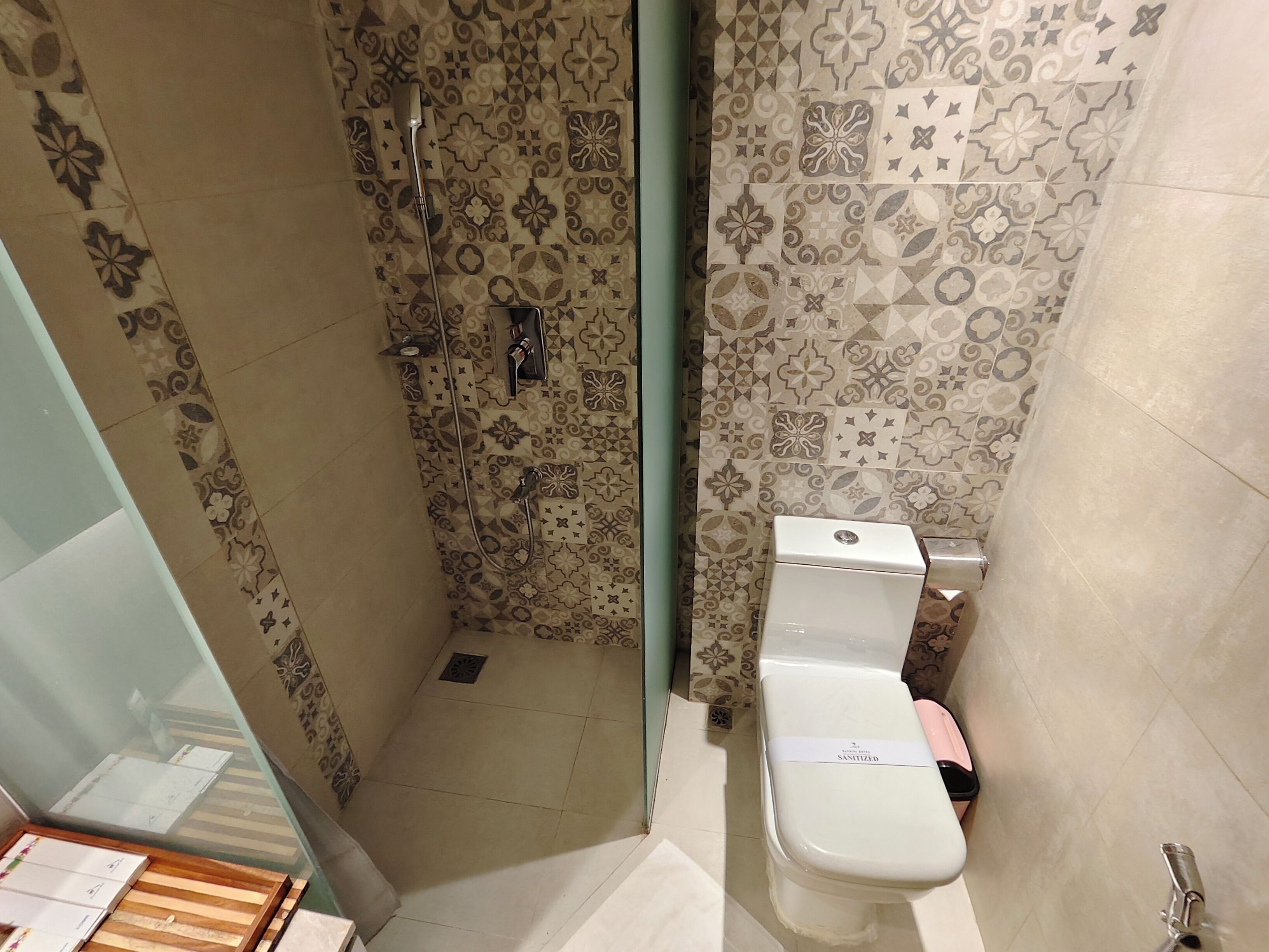 Ein Badezimmer mit gemusterten Fliesen, einer Dusche und einem WC.