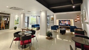 A modern hotel lobby with a seating area, a television, and a glass partition with a view of the outdoors. - Hotel Nandini (Dhaka)