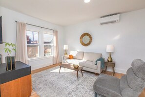A modern living room with a sofa, armchairs, a coffee table, and a side table with lamps. - Modern Loft in Historic Birdtown - Unit 5 (Lakewood)