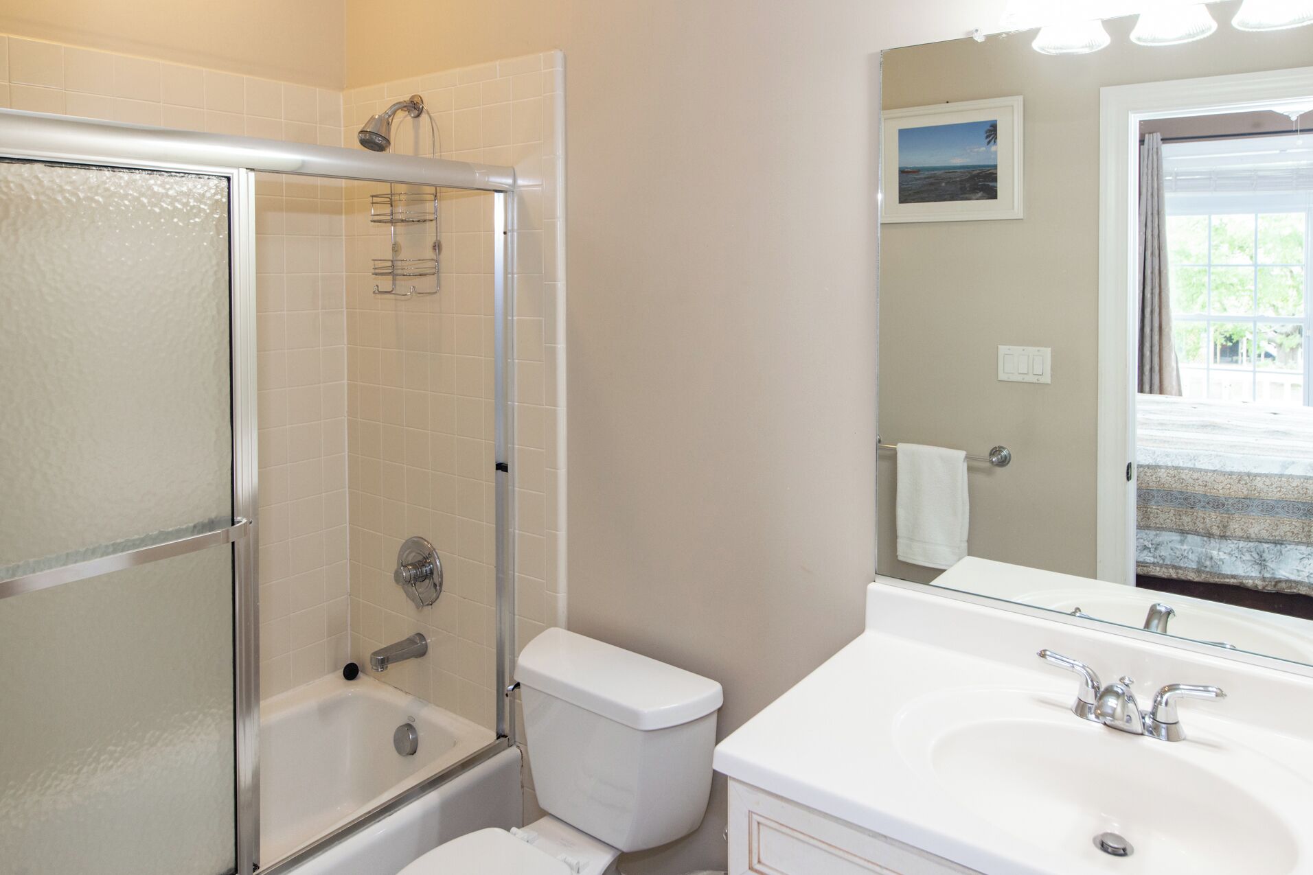 A bathroom with a glass-enclosed shower, a white toilet, and a sink with a mirror.