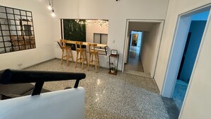 A modern interior with a dining area, a kitchen, and a hallway leading to another room. - Rustik House (Medellín)