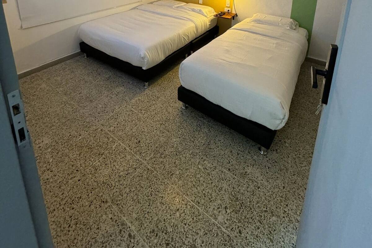 Une chambre avec deux lits, un plafond à motifs, un luminaire suspendu et un mur orné de formes géométriques.