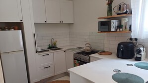 Eine kleine Küche mit weißen Schränken, einem Herd, einer Spüle und einer Mikrowelle.