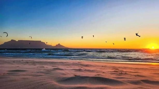 A beach with kites flying, a sunset, and a distant mountain. - A nestled retreat to create memories (Cape Town)