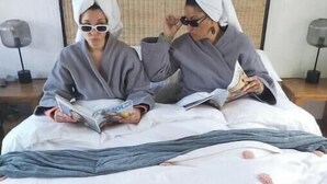 Two people sitting on a bed with a white sheet and pink polka dots, reading a book. - A nestled retreat to create memories (Cape Town)