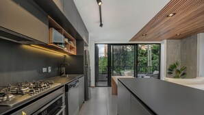 Une cuisine moderne équipée d’une cuisinière à gaz, d’un four et d’appareils électroménagers intégrés. Une grande fenêtre offre une vue sur l’extérieur.