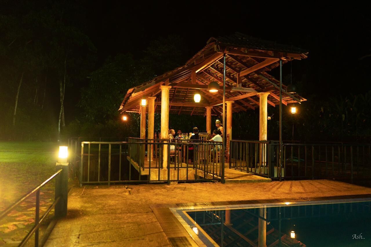 Un espacio al aire libre techado con piscina, pilares de madera y barandilla.