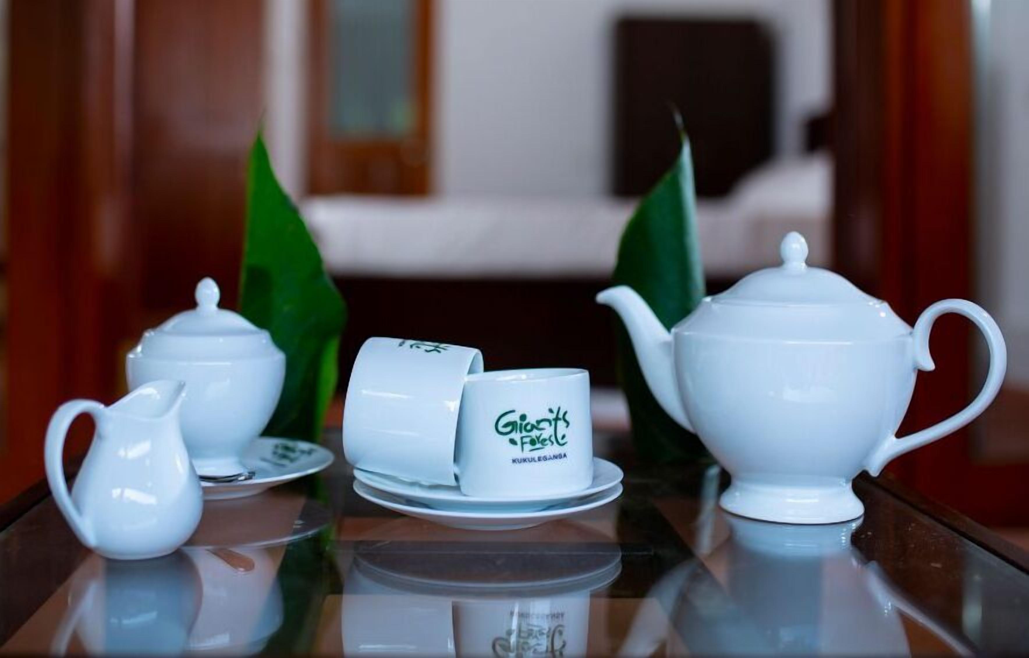 A tea set on a reflective surface with a logo on the cup.