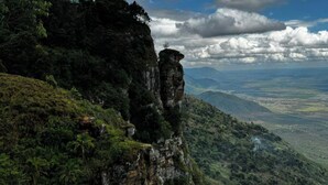 A mountainous landscape with a prominent cliff and a view of a valley below.