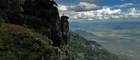 A mountainous landscape with a prominent cliff and a view of a valley below.