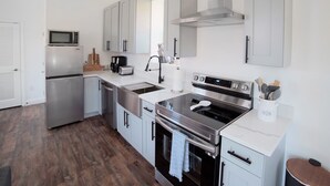 Een moderne keuken met roestvrijstalen apparatuur, grijze kastjes en een wit aanrecht.