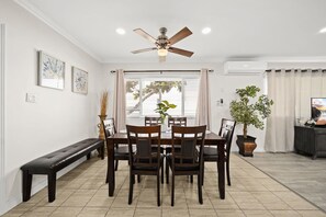A dining area with a table, chairs, a ceiling fan, and a bench.