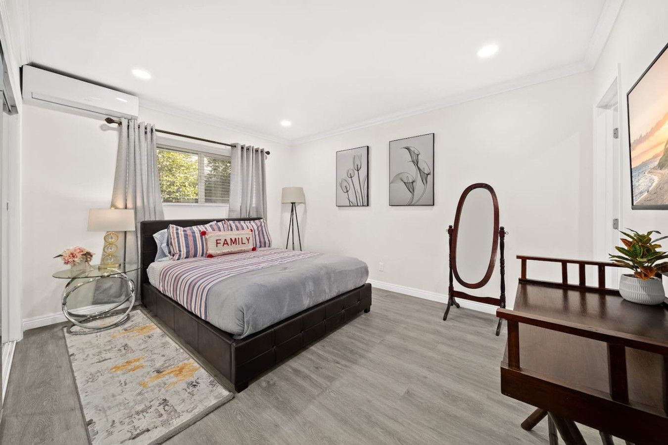 A bedroom with a bed, bedside tables, a mirror, and artwork on the walls.
