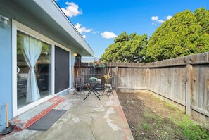 Ein Garten mit Terrasse, Holzzaun und einem großen Baum.