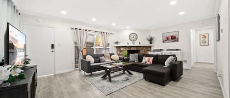 A modern living room with a sofa set, a coffee table, and a flat-screen TV.