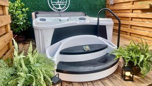 Un jacuzzi con un logotipo, rodeado de vallas de madera y helechos.