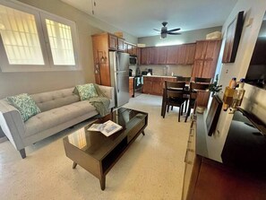 A modern living room with a sofa, coffee table, and kitchen area with cabinets and appliances. - GIVA-Green Island Villa just step away to beach! (Isla Verde)
