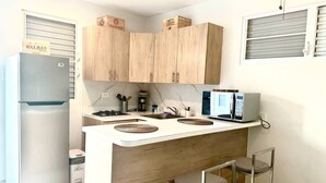 Una cocina compacta con armarios de madera, un microondas integrado y un refrigerador.