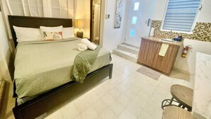 Una habitación de hotel con cama, baño y kitchenette.