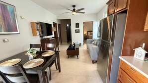 A modern kitchen with a large refrigerator, wooden cabinets, and a dining area with a table and chairs. - GIVB-Updated Family Budget unit just step away from the beach! (Carolina)