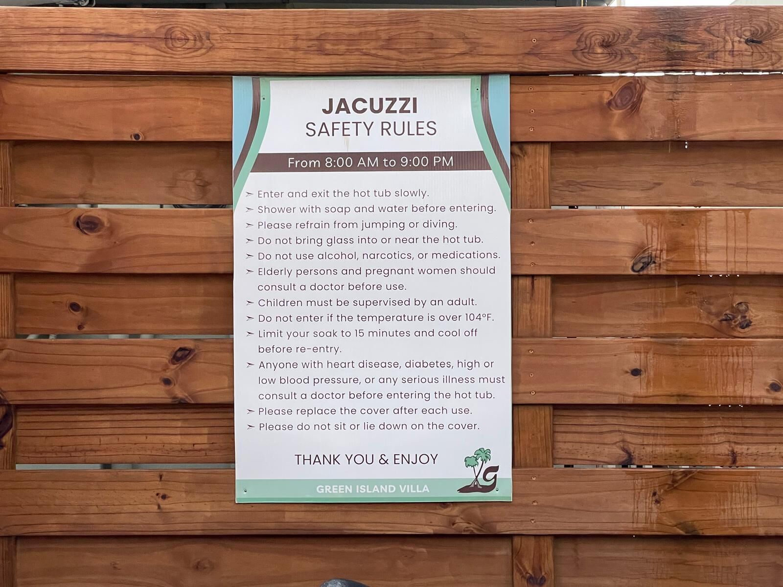 A wooden fence with a sign listing jacuzzi safety rules.