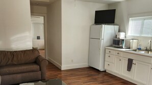 A compact living space with a ceiling fan, a kitchenette with a refrigerator, microwave, and sink, a brown leather couch, and a glass-top coffee table. - Cozy 1 bedroom cabin in peaceful Trinity Center with AC (Trinity Center)
