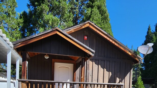 A small wooden cabin with a porch, a door, and a satellite dish. - Cozy 1 bedroom cabin in peaceful Trinity Center with AC (Trinity Center)