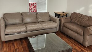 A modern living room with two sofas, a glass coffee table, and a wooden floor. - Cozy 1 bedroom cabin in peaceful Trinity Center with AC (Trinity Center)