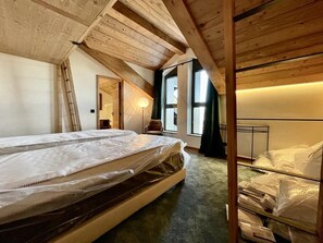 Un dormitorio con un espacio de descanso elevado, una escalera y una cama con colchón.