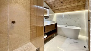 A modern bathroom with a freestanding bathtub, wooden ceiling, and marble flooring. - 350 - Suite The West - Luxury residence (Courchevel)