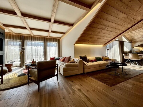 Un salón amplio con suelo de madera, techo alto y un gran sofá.
