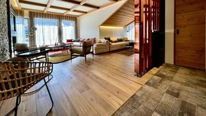 A spacious living area with a high ceiling, wooden beams, a large sofa set, and a wooden partition. - 350 - Suite The West - Luxury residence (Courchevel)
