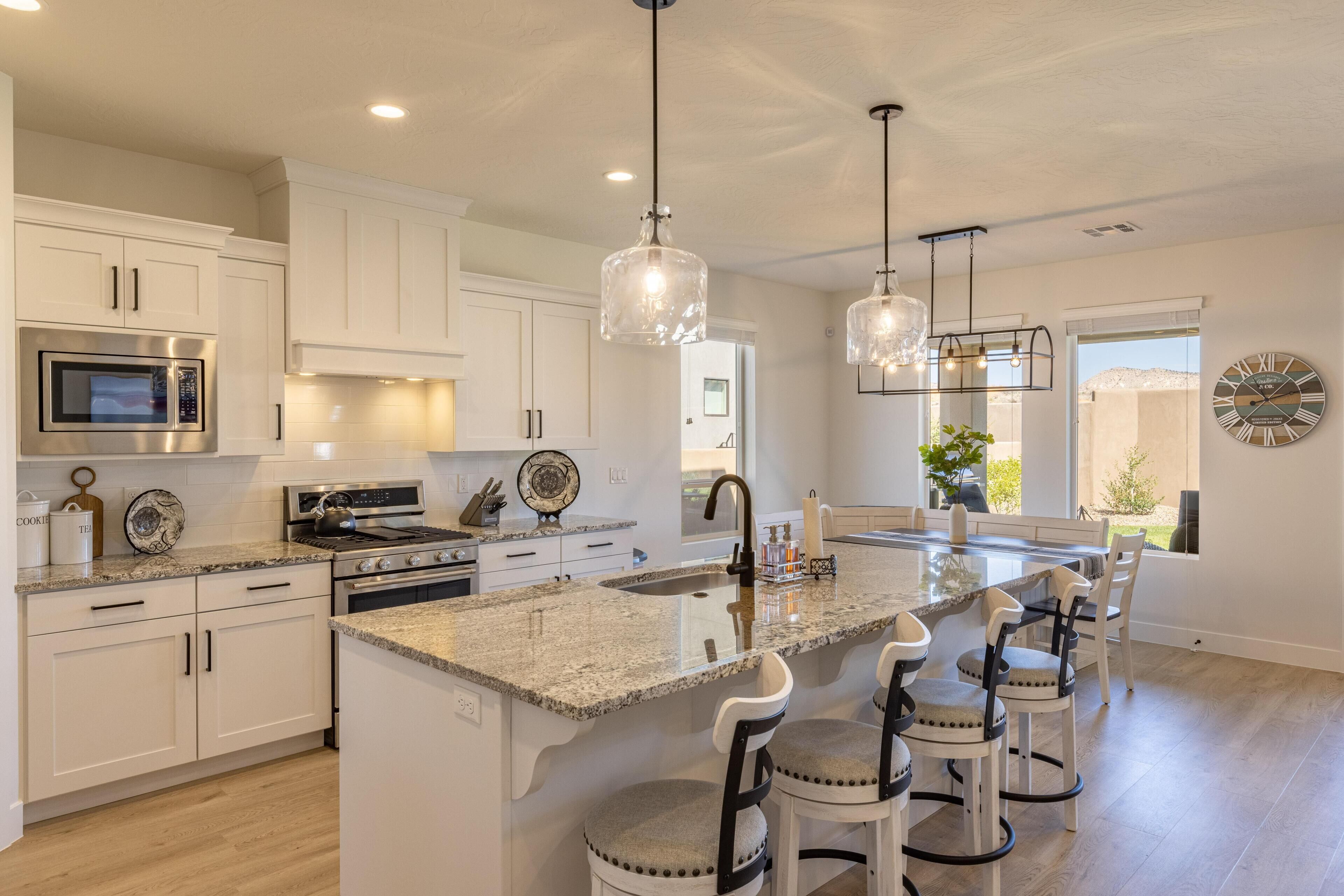 A modern kitchen with white cabinetry, stainless steel appliances, and a central island with bar stools.
