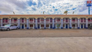 Un motel con varios balcones, un estacionamiento y cielo despejado.