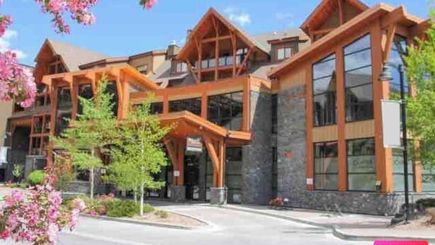 A multi-story building with a wooden facade, large windows, and a stone base.