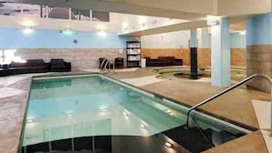 An indoor swimming pool with a clear water view, a lounge area with sofas, and a reception desk.
