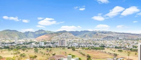 Vista de un paisaje urbano con montañas, edificios residenciales y una zona verde.