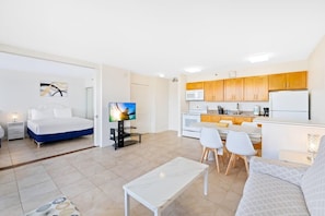 Een moderne, compacte woonruimte met een bed, een televisie, een eethoek en een kitchenette.
