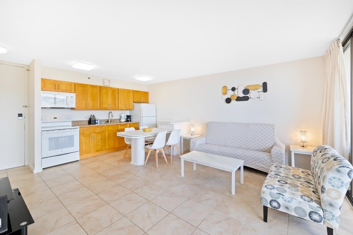 Um espaço de estar compacto com cozinha americana, área de jantar e sala de estar com sofá e poltrona estampada.