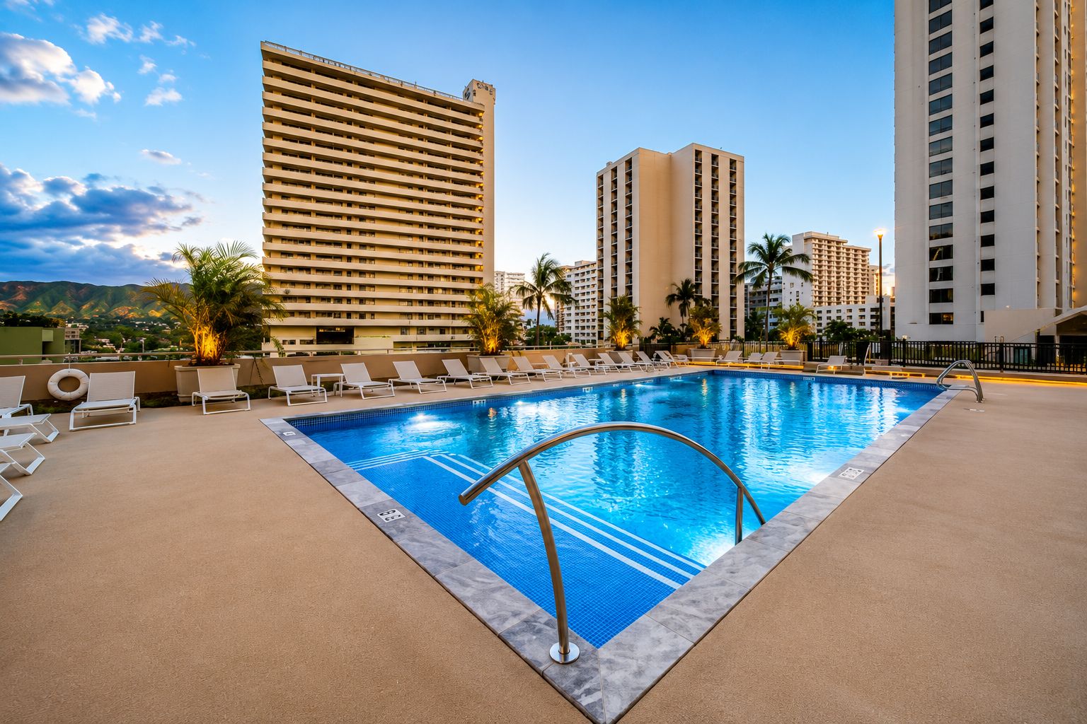 A swimming pool with lounge chairs and a view of tall buildings.