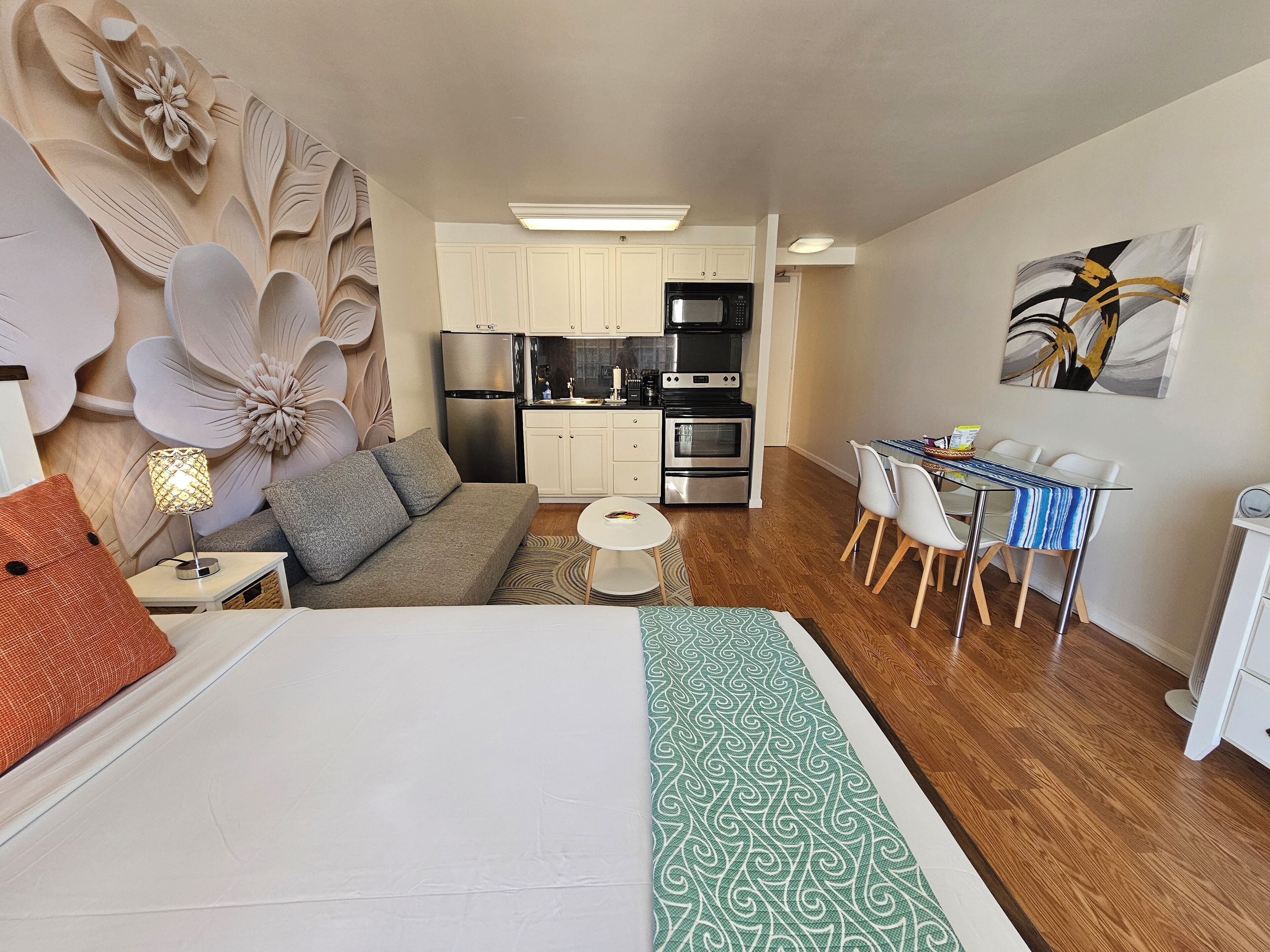 Un espace de vie compact comprenant un coin cuisine, un coin repas et une chambre.