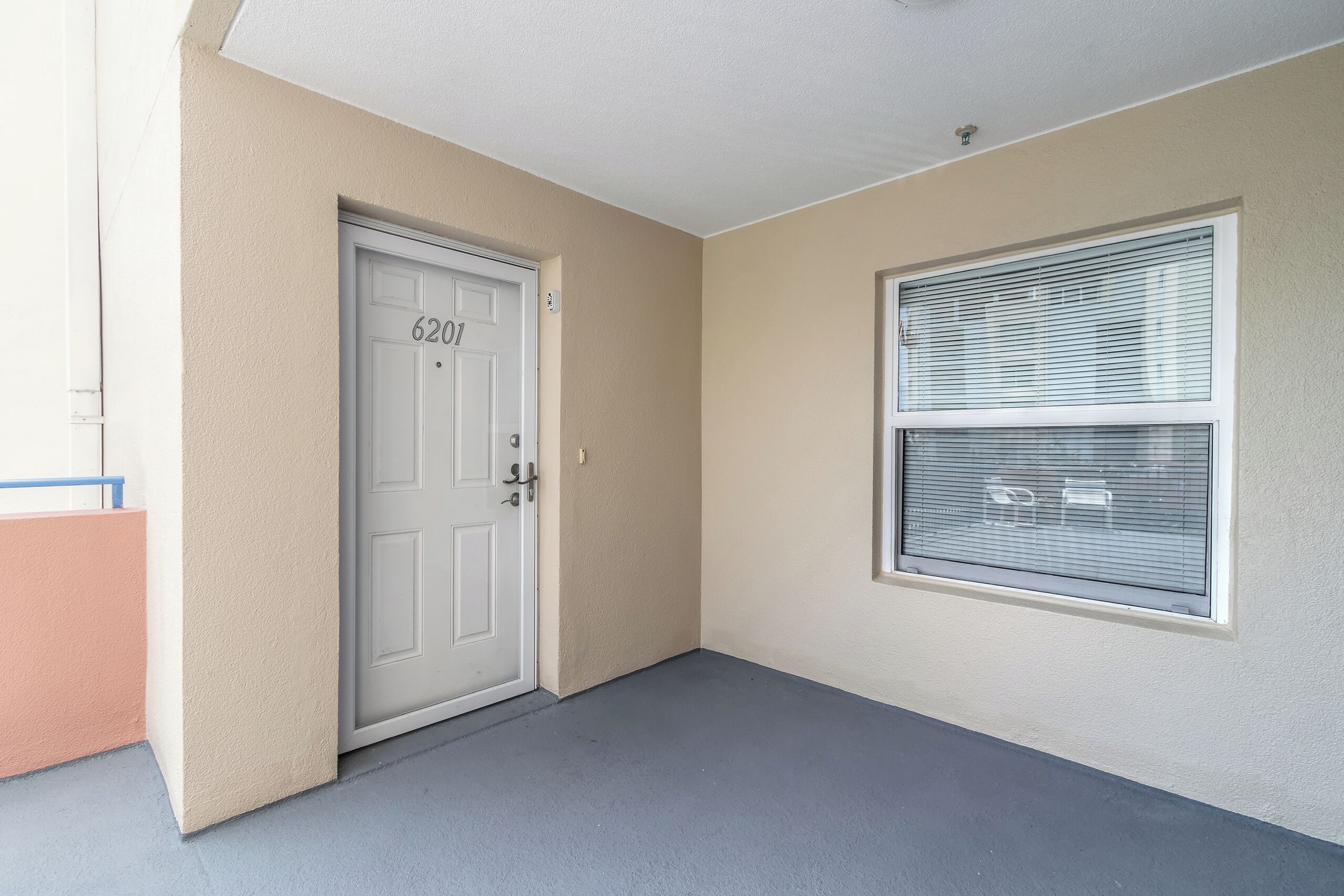 A hallway with a door labeled "6201," a window with blinds, and a light-colored wall.