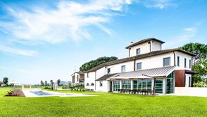 A modern building with a swimming pool, a covered outdoor seating area, and a well-maintained lawn. - Best Of Tuscany between Chianti, Pisa, Florence 7 (San Miniato Basso)