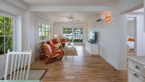 A spacious living area with a sofa, chairs, a TV, and a view of the outdoors. - PARADISE SHORES (Islamorada)