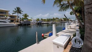 A marina with boats docked, a white building with a balcony, and palm trees. - PARADISE SHORES (Islamorada)