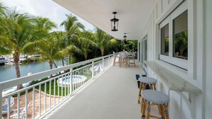 A balcony with a view of a pool, palm trees, and boats. - PARADISE SHORES (Islamorada)